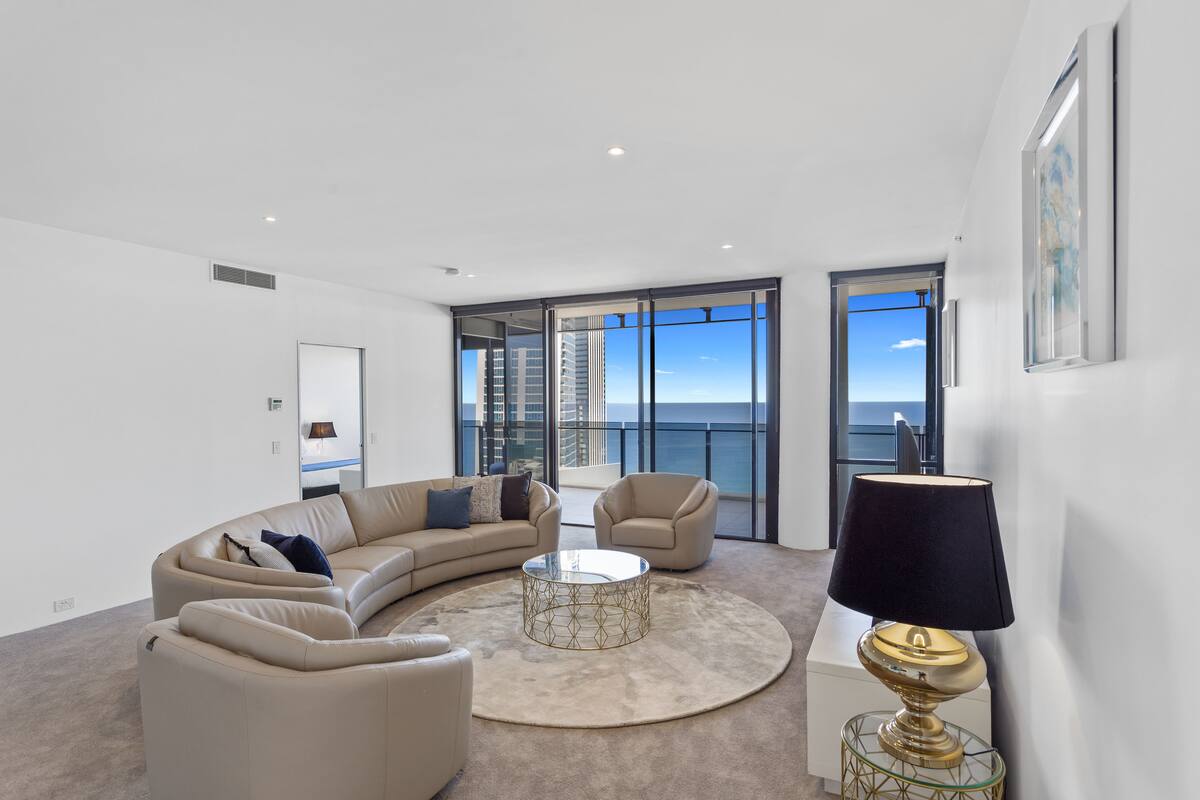 A modern living room with a curved beige sofa, a round coffee table, and a lamp.