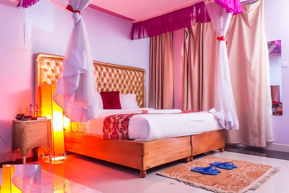 A bedroom with a bed, bedside table, and curtains.