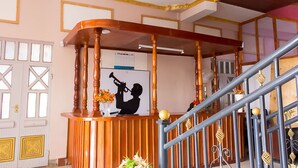 Un comptoir d’accueil avec un revêtement en bois, une silhouette encadrée d’un homme jouant de la trompette et un panneau d’affichage avec un calendrier.
