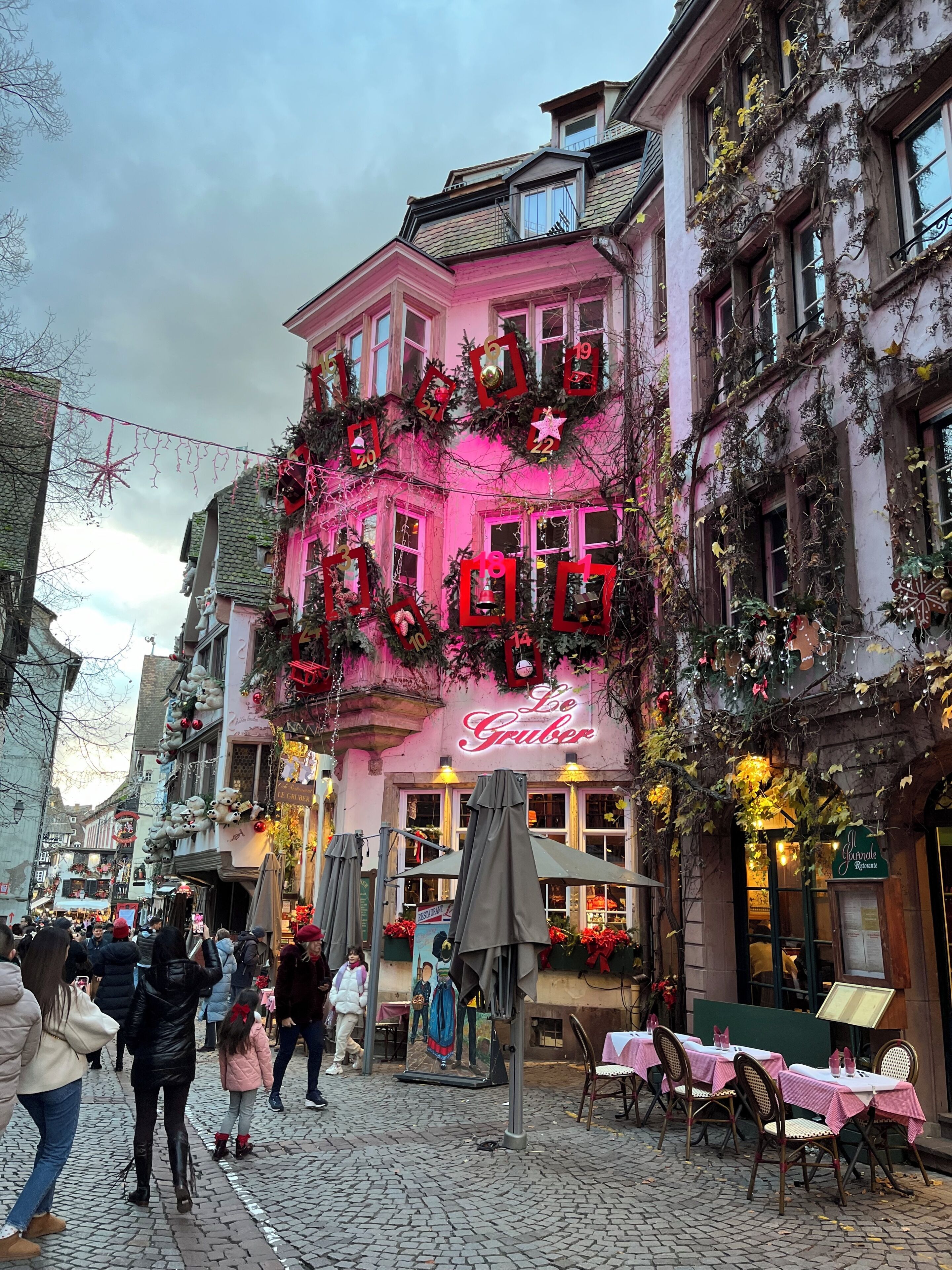 A building with a sign reading 'Le Gruber' and a restaurant sign. There are outdoor tables and chairs set up.
