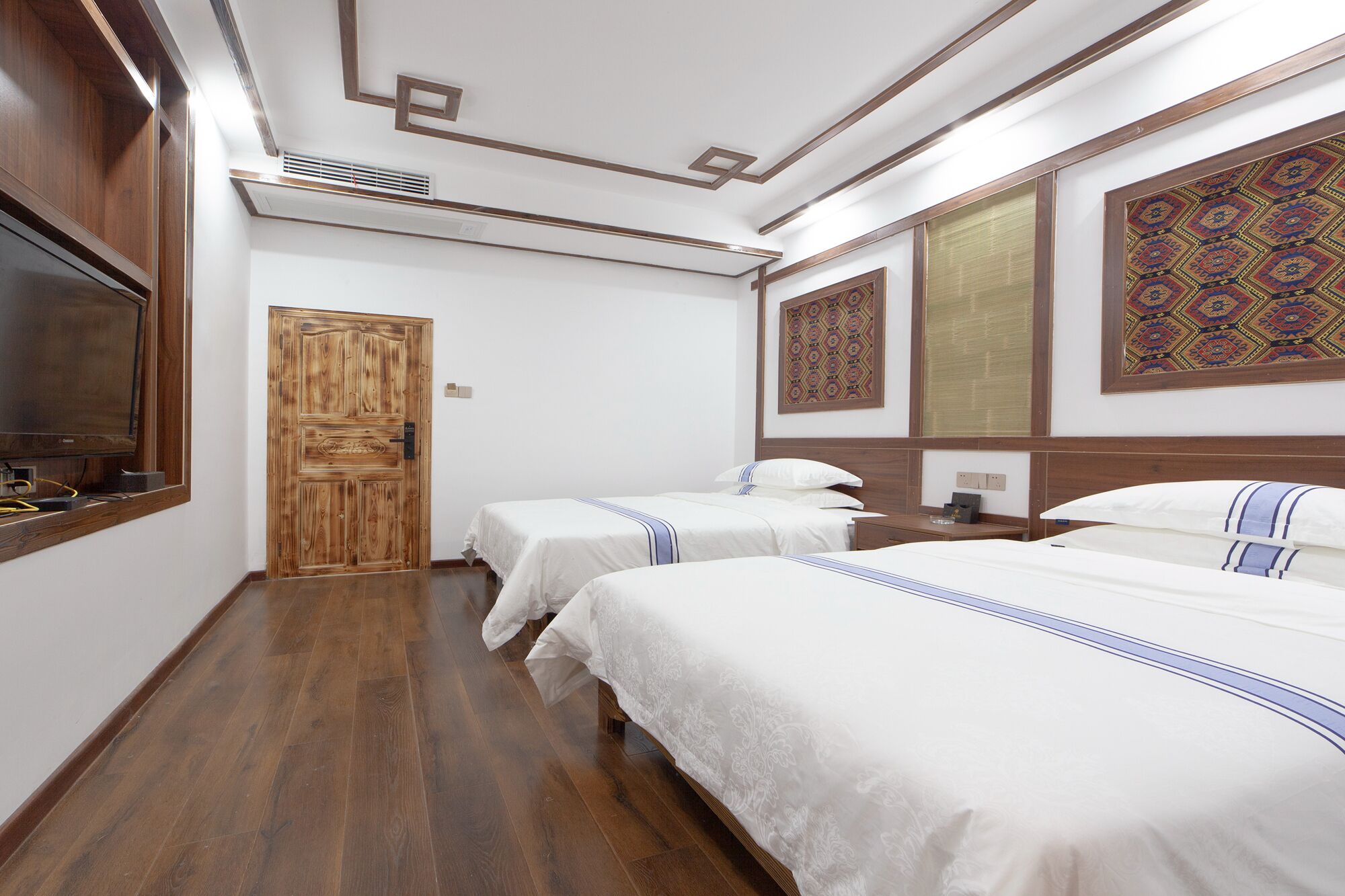 Una habitación de hotel con dos camas, un armario de madera, un televisor y decoración mural.