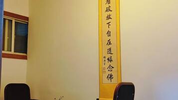 A room with a table and two chairs, a window, and a wall-mounted sign with Chinese characters.