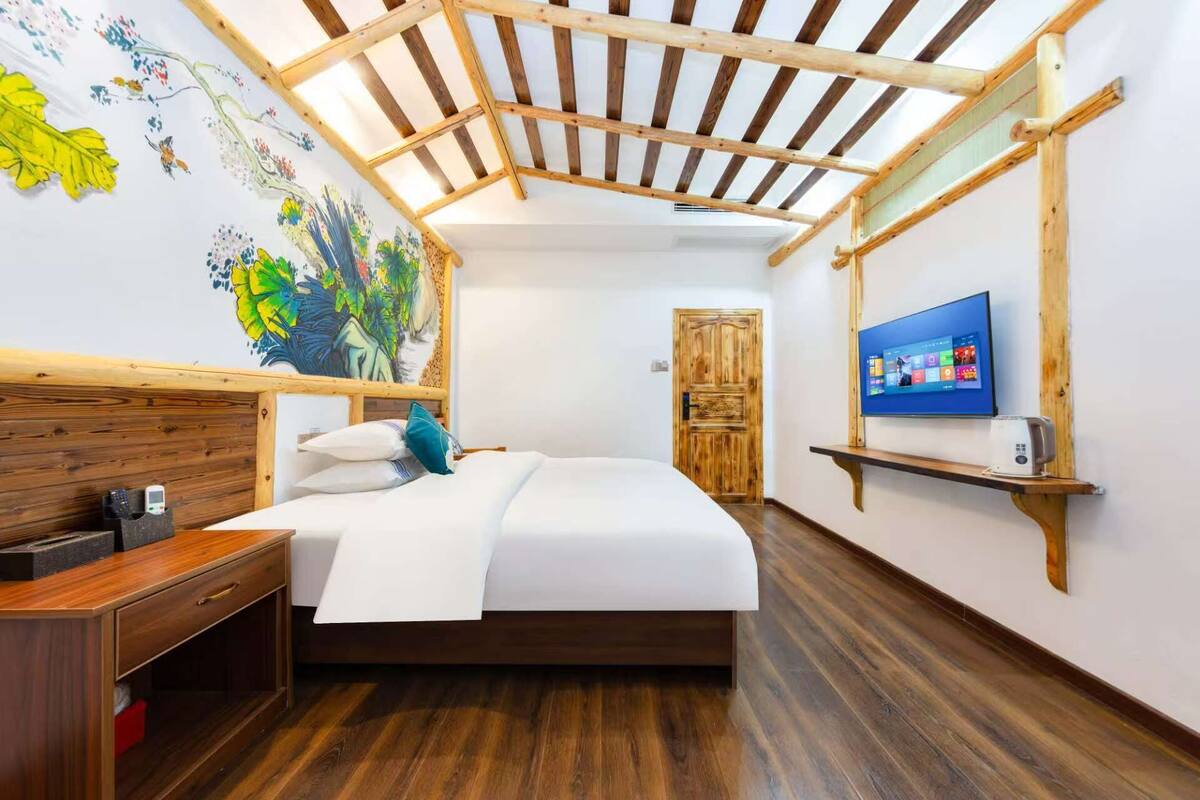 Une chambre d’hôtel moderne avec un plafond en bois, un grand lit, une télévision et un bureau en bois.
