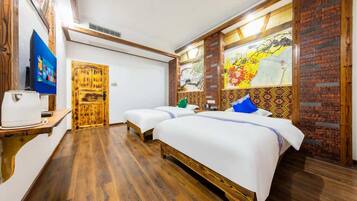 Habitación de hotel con dos camas, suelo de madera, televisor y puerta de madera.