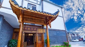 A traditional wooden entrance with a tiled roof, a signboard, and a small garden area with plants and rocks. - Zhangjiajie Shi Guang Zhi Wai Boutique Hotel (Zhangjiajie)