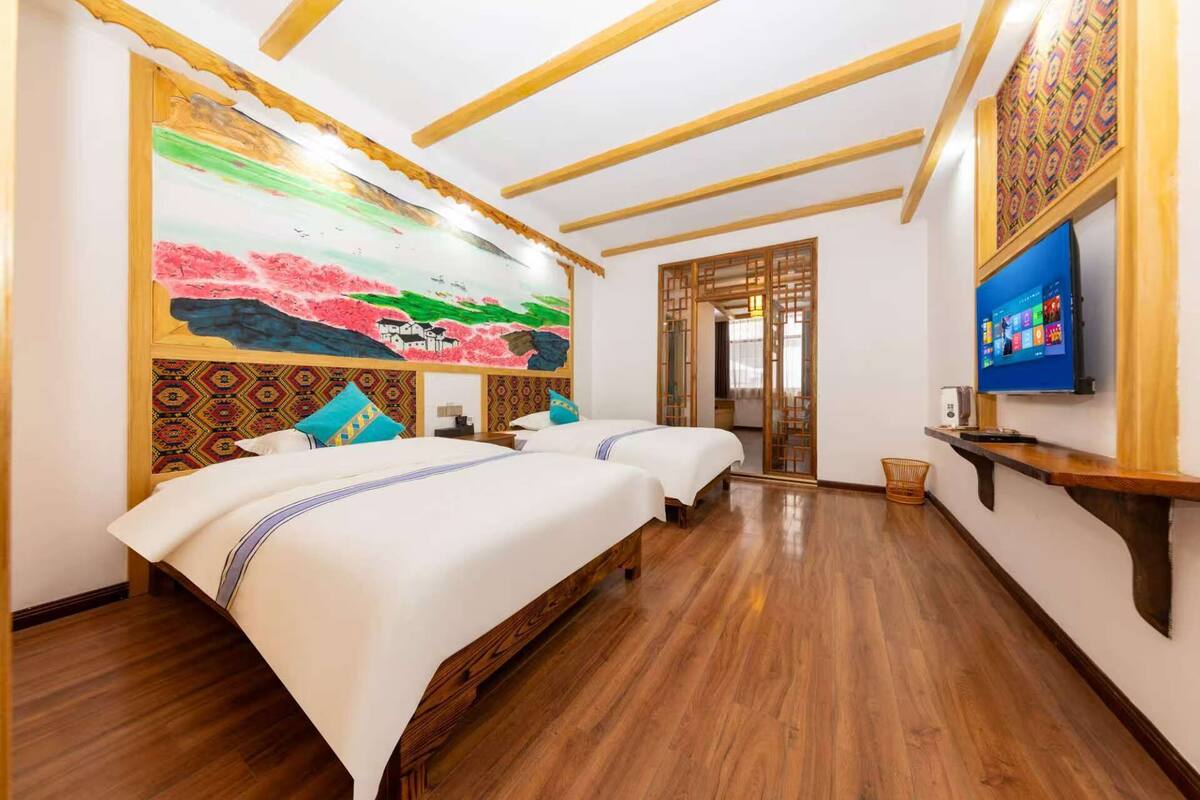Une chambre d’hôtel avec deux lits, une grande fresque murale, un téléviseur et un plafond en bois.