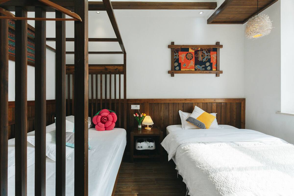 Une chambre avec deux lits, une tête de lit en bois, une table de chevet avec une lampe et une œuvre d’art accrochée au mur.