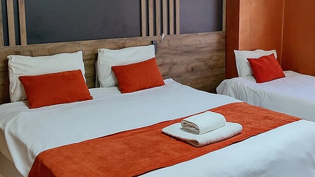 Una camera d'hotel con due letti, un grande pannello a parete e una lampada a soffitto.