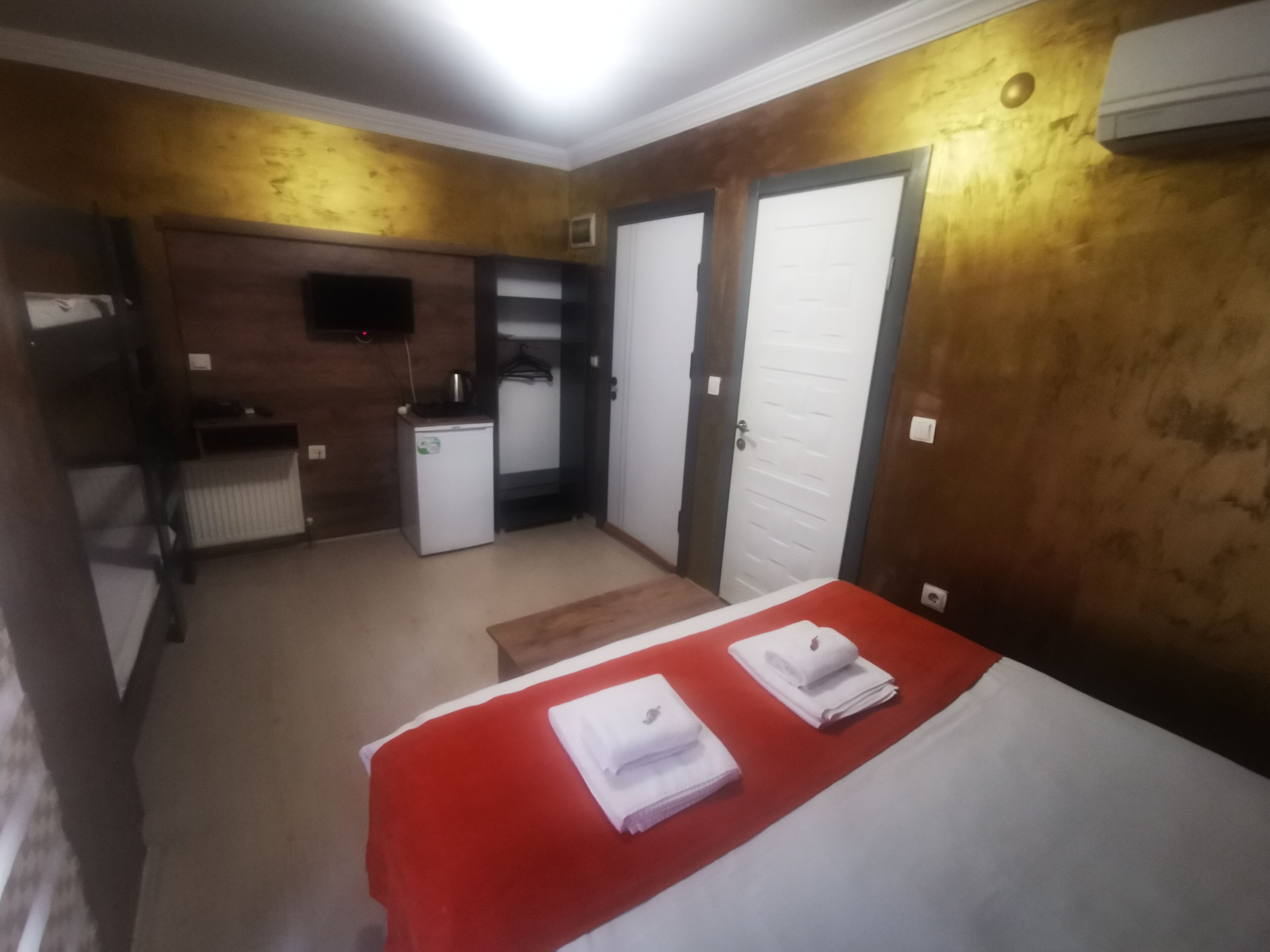 Une chambre d’hôtel de taille réduite, comprenant un lit, une petite kitchenette, une armoire et un téléviseur.