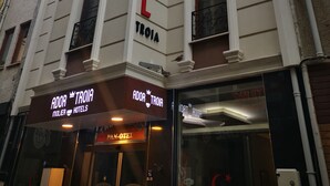 Un hotel chiamato 'Ador Troia' con una facciata moderna, ampie finestre e balconi.