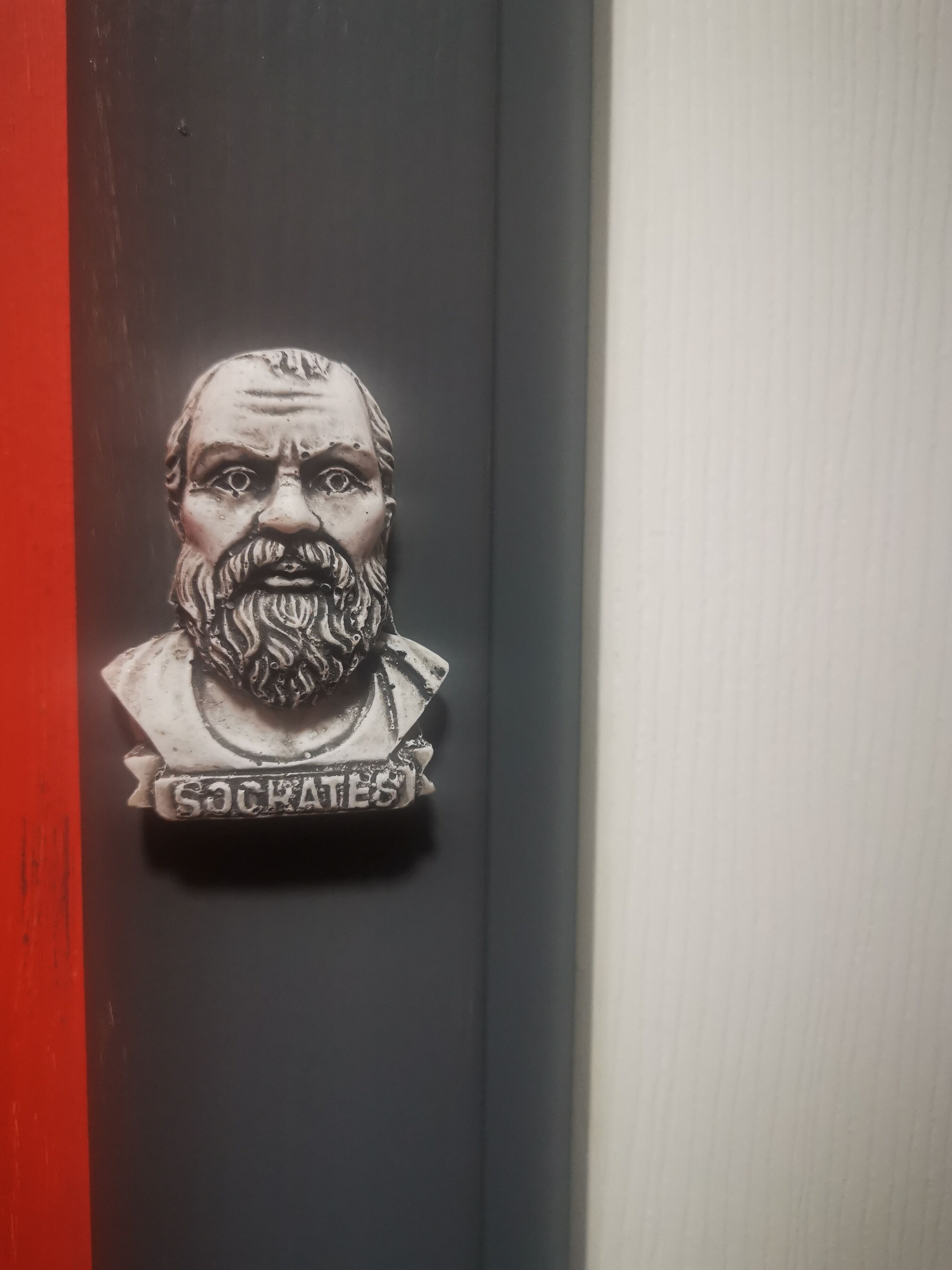 A bust of Socrates with the inscription "SOCRATES" on a dark door.