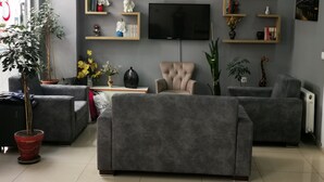 Un soggiorno moderno con divani grigi, una televisione a schermo piatto ed elementi decorativi su mensole.