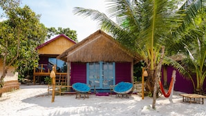 A beach house with a thatched roof, two blue cushioned chairs, and a hammock. - Bamboo Jam (Koh Rong Sanloem)