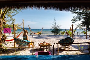 A beachside setting with two lounge chairs, a hammock, and a table with food items. - Bamboo Jam (Koh Rong Sanloem)