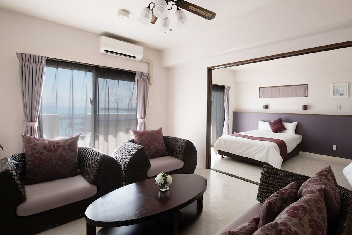 Une chambre d’hôtel avec un balcon, un canapé, un lit et une table basse.