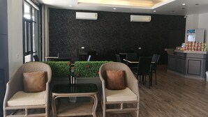 A modern hotel lobby with wicker chairs, a reception desk, and a green plant wall. - Mana Residence (Hat Yai)