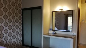 A hotel room with a bed, a bedside table with a mirror, and a wardrobe. - Mana Residence (Hat Yai)