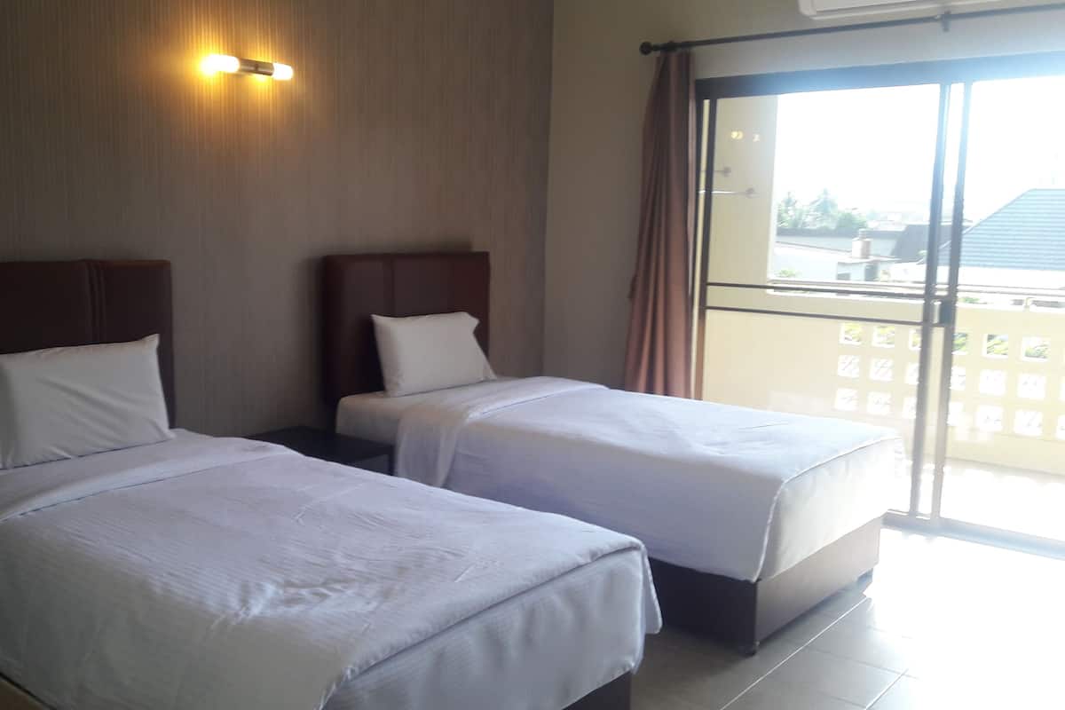 Habitación de hotel con dos camas, un ventanal grande y vistas al exterior.