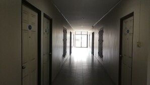 A corridor with doors on both sides, leading to a bright room at the end. - Mana Residence (Hat Yai)