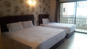 A hotel room with two beds, a patterned wall, and a view through a balcony. - Mana Residence (Hat Yai)