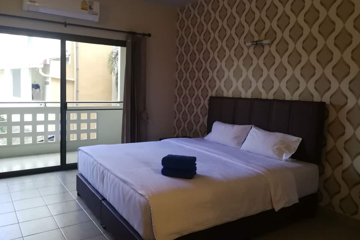 Una habitación de hotel con cama, pared estampada y puerta corrediza de vidrio al exterior.