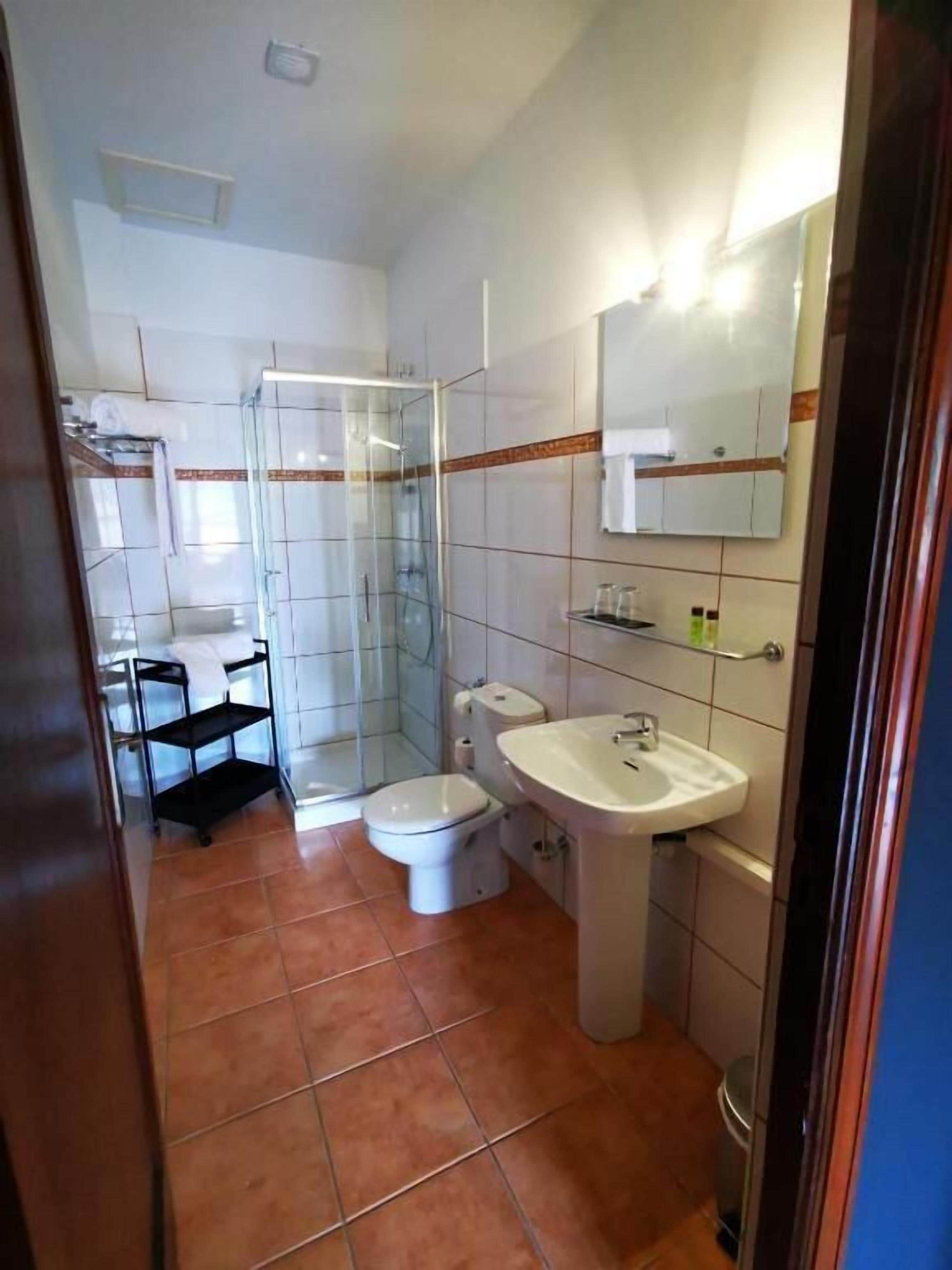 Un baño con ducha de vidrio, inodoro y lavabo.
