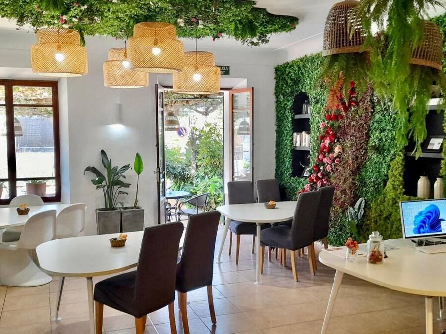 Un comedor moderno con mesas redondas, sillas negras y lámparas de mimbre colgantes.