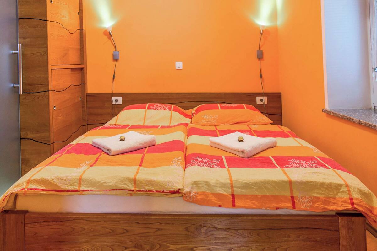 A double bed with a striped bedspread and two towels, wooden headboard, and two wall-mounted lights.