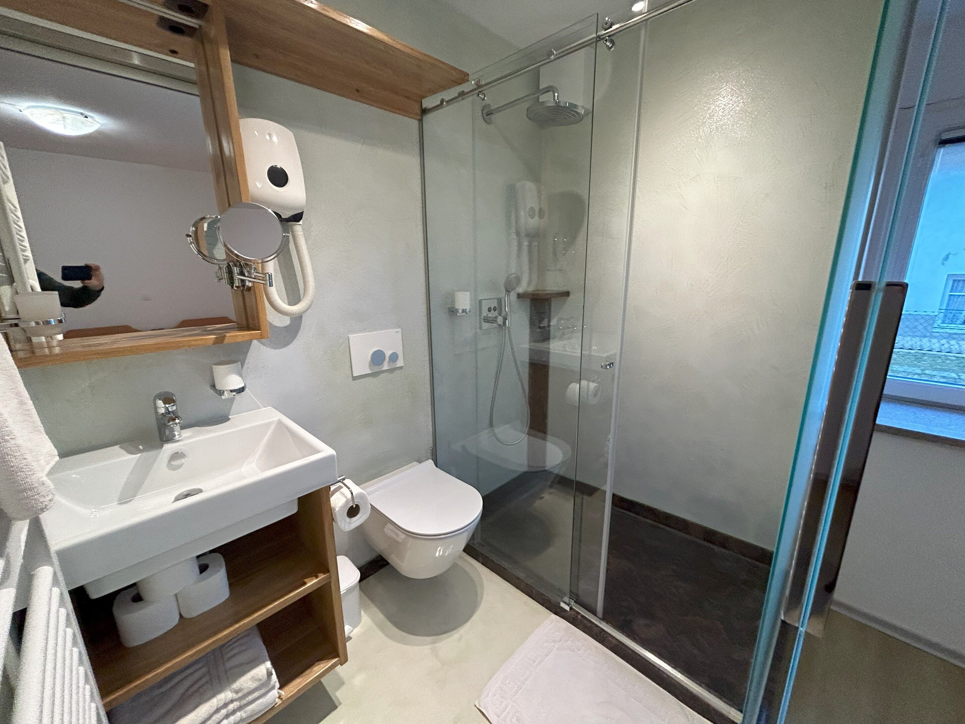 A modern bathroom with a glass-enclosed shower, a white sink, and a toilet.