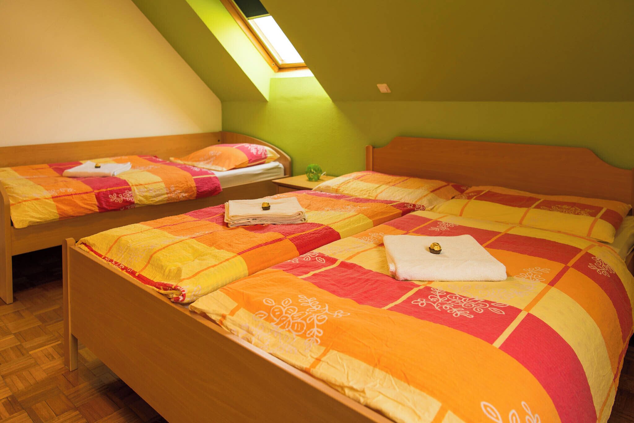 A room with two beds, each with a colorful quilt, a skylight, and a wooden headboard.