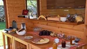 Una mesa buffet de madera con diversos alimentos, incluyendo una tabla de embutidos, salsas y bebidas.