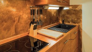 Una cocina con un lavamanos de acero inoxidable, armarios de madera y una estufa empotrada.