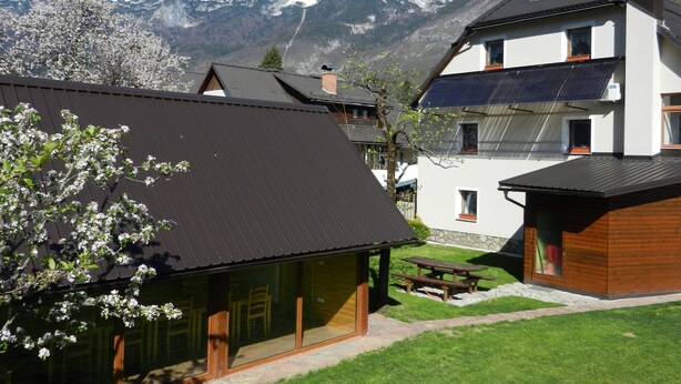 Un edificio moderno con techo inclinado, ventanas grandes y un patio con mesa y sillas.