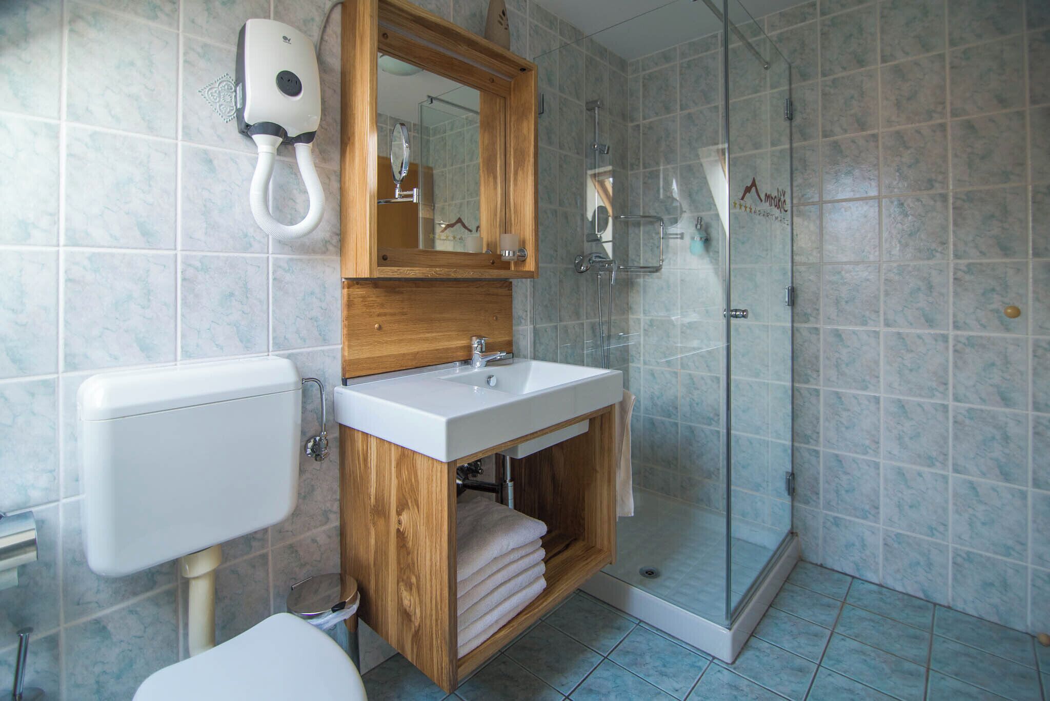 A bathroom with a wooden vanity, a glass shower enclosure, and a toilet.