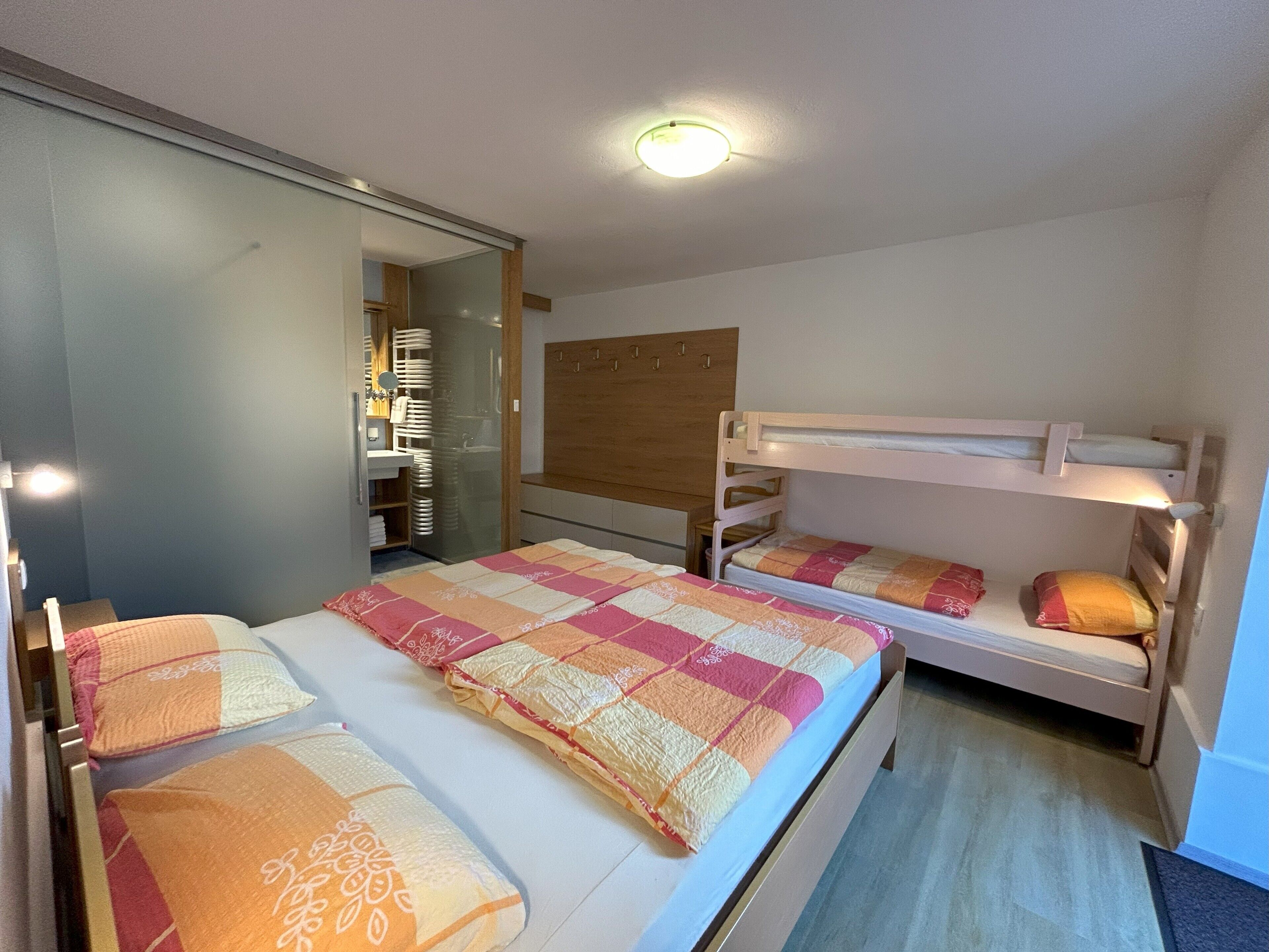 Een slaapkamer met een stapelbed, een grote spiegel, een houten hoofdbord en een nachtkastje.