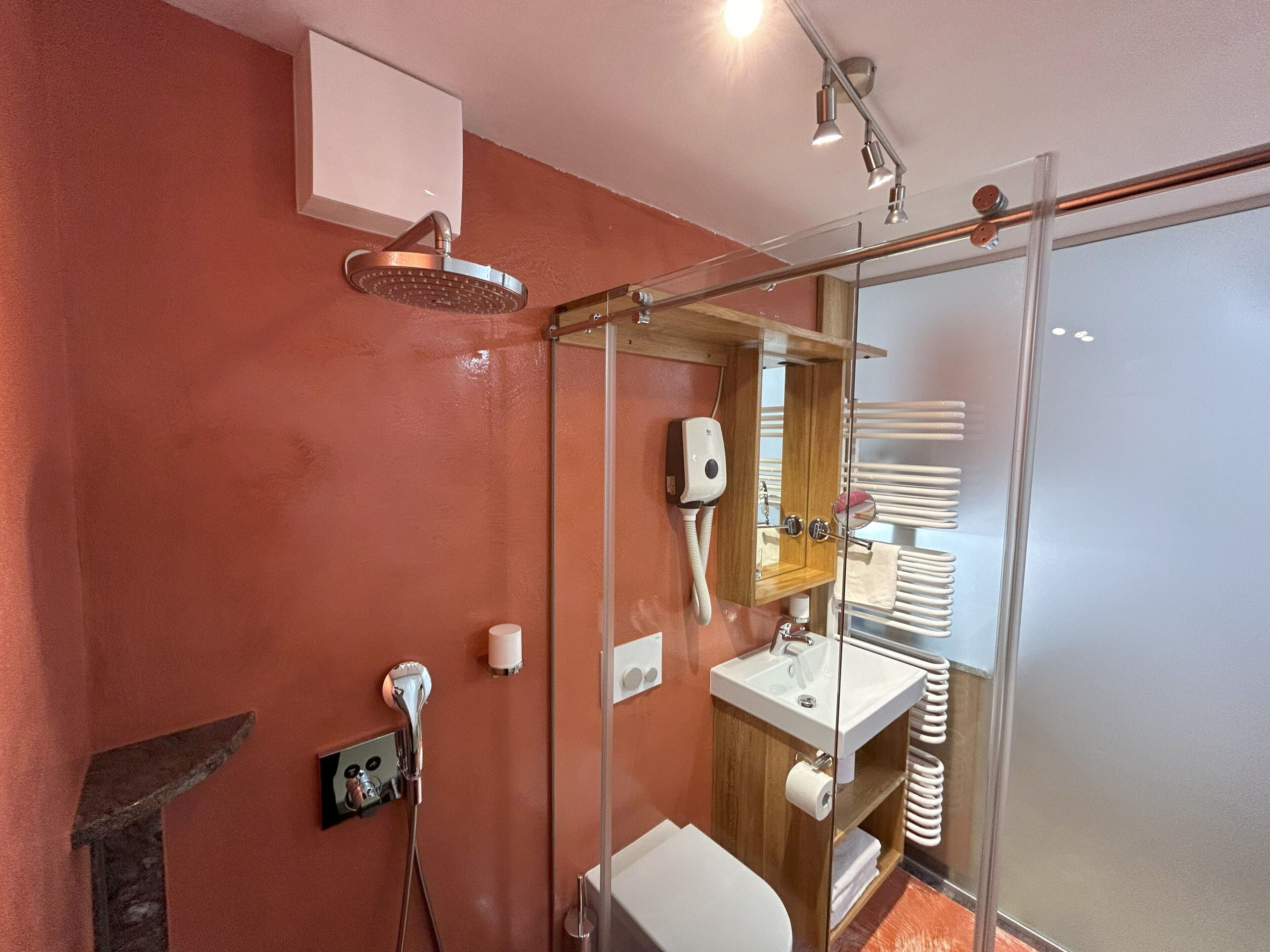 A modern bathroom with a glass-enclosed shower, a wooden vanity, and a white sink.