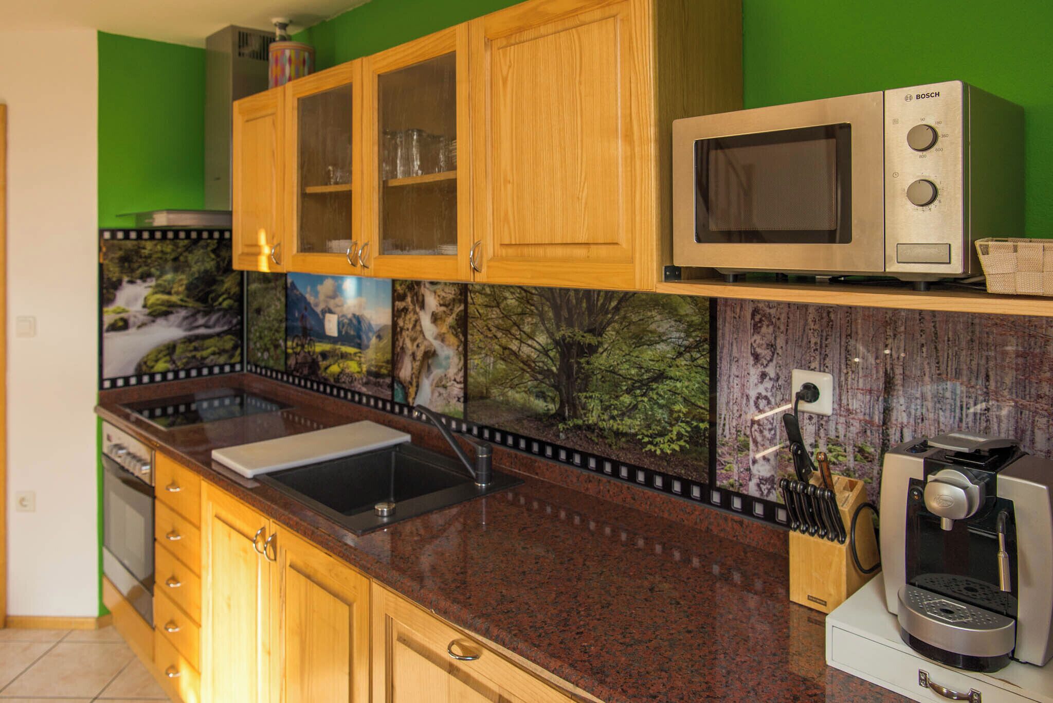 A kitchen with wooden cabinets, a microwave, a coffee machine, and a sink.