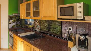 A kitchen with wooden cabinets, a microwave, a coffee machine, and a sink.