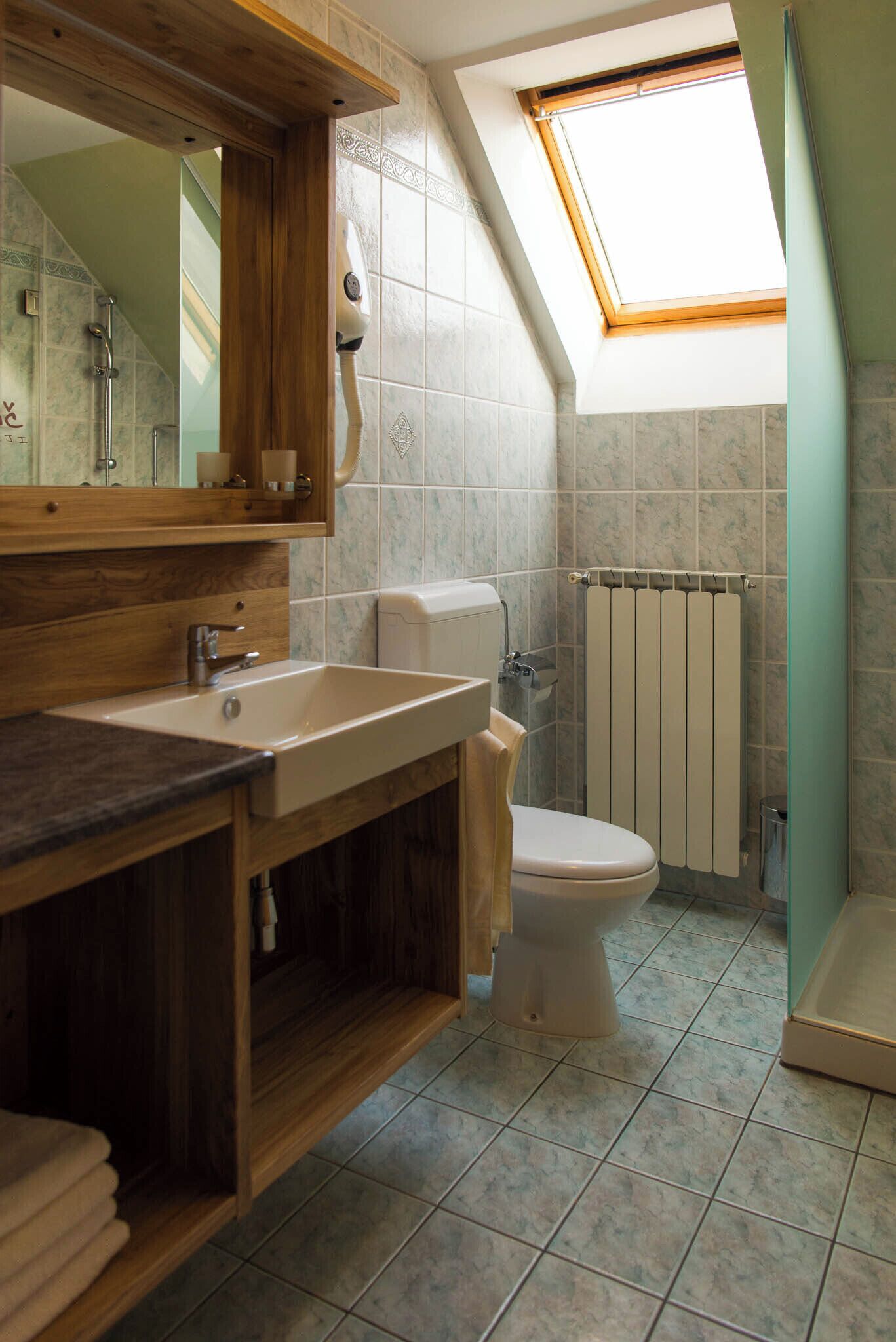 Une salle de bain avec un puits de lumière, un meuble-lavabo en bois, des toilettes et un radiateur.
