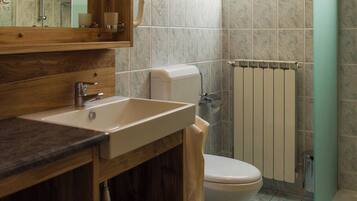 Une salle de bain avec un puits de lumière, un meuble-lavabo en bois, des toilettes et un radiateur.
