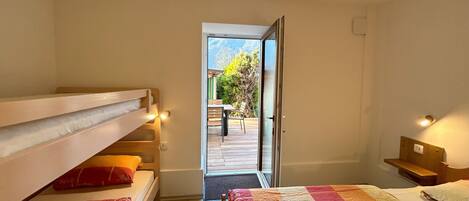 A bedroom with bunk beds, a large window, and a view of an outdoor deck.