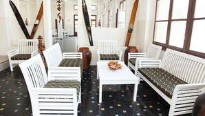 Ein Zimmer mit weißen Möbeln, Fliesenboden und Surfbrettern an der Wand.
