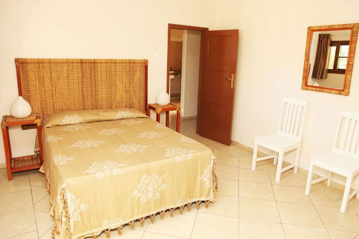 A bedroom with a bed, two nightstands, a chair, a door, and a mirror on the wall.