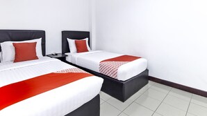 A hotel room with two beds, each with a black headboard, white bedding, and red accents.