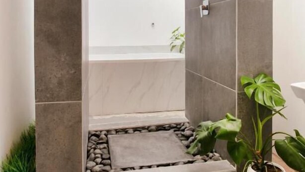 A modern bathroom with a bathtub, a shower area, and a small garden space with plants.