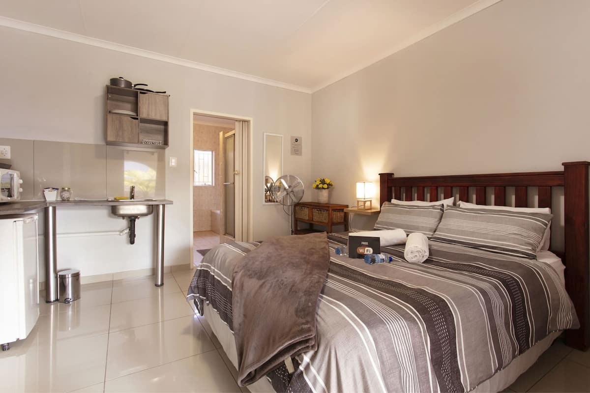 Une chambre d’hôtel avec un lit, une table de chevet, une lampe et vue sur la salle de bain.