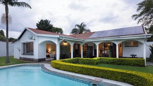 A house with a swimming pool, solar panels, and a well-maintained garden.