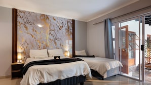 A modern hotel room with two beds, a large window, and a view of the outside.
