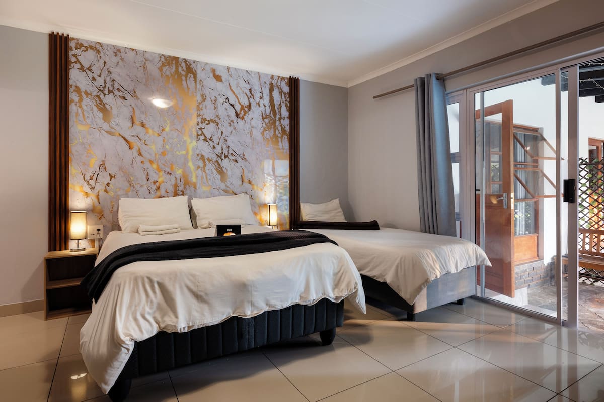 Une chambre d’hôtel moderne avec deux lits, une grande fenêtre et une vue sur l’extérieur.