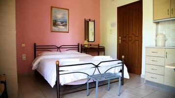 A bedroom with a bed, a bedside table, a mirror, a dresser, and a door.